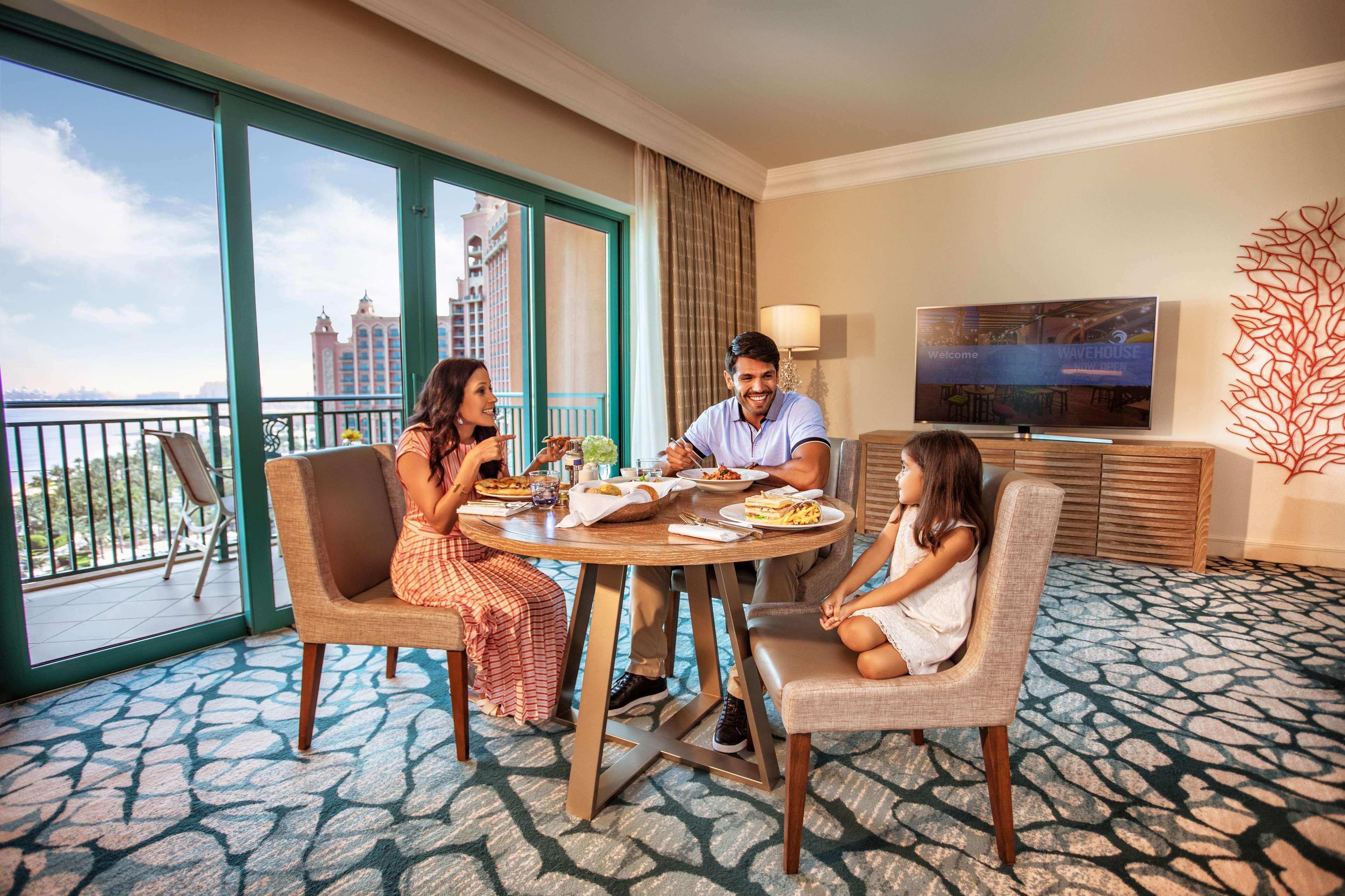 Hotel Atlantis, The Palm Dubai Esterno foto The image shows a family dining together in a modern, well-furnished hotel room. There are three people around a round table: an adult male and female, and a young girl. They appear to be enjoying a meal, with various dishes set out on the table. Beh