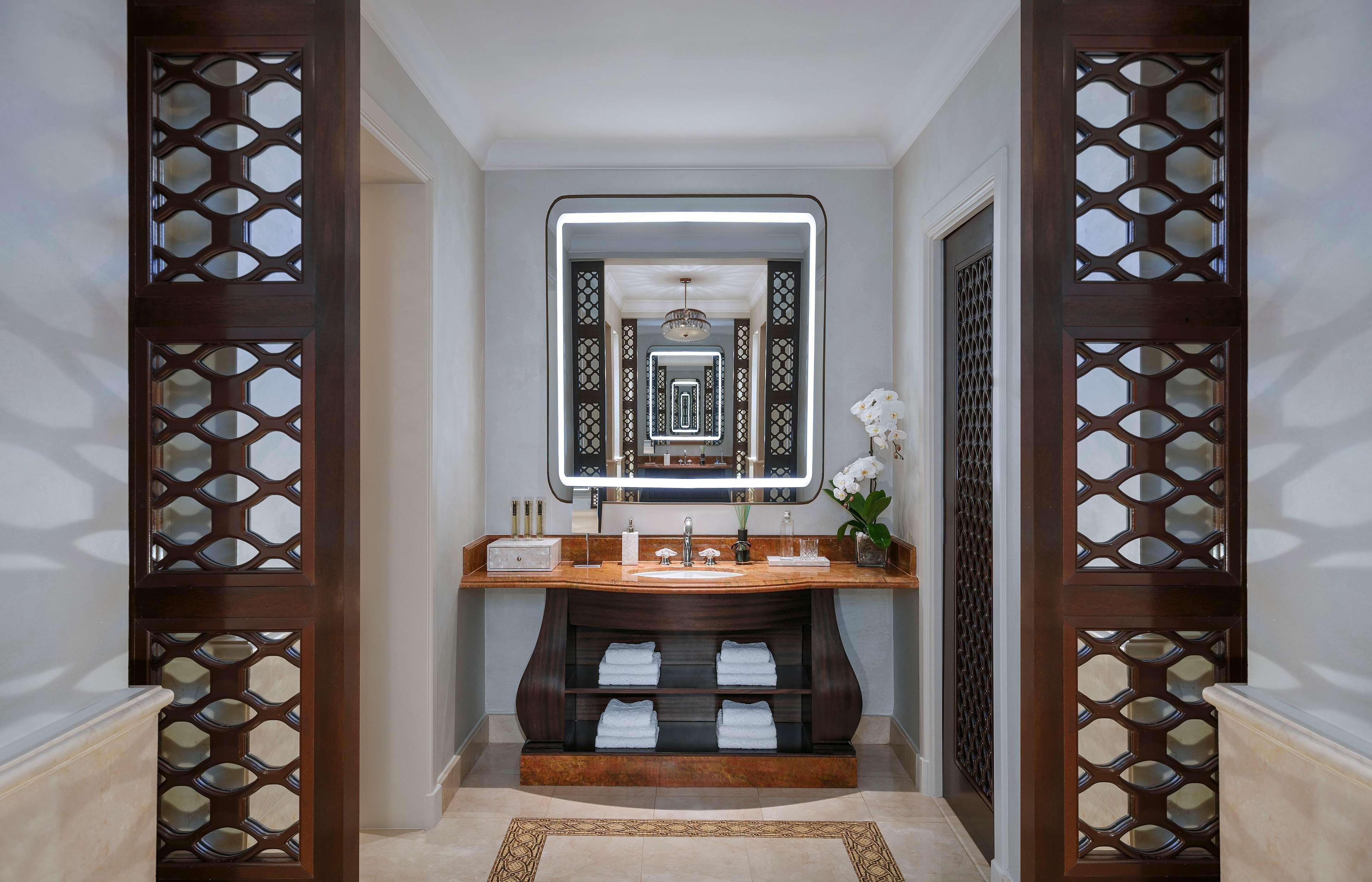 Hotel Atlantis, The Palm Dubai Esterno foto The photo shows a stylish bathroom with a modern design. In the center, there is a wooden vanity with a sink, flanked by neatly stacked white towels. Above the vanity is a large, illuminated mirror that enhances the space. To the sides, intricate woo