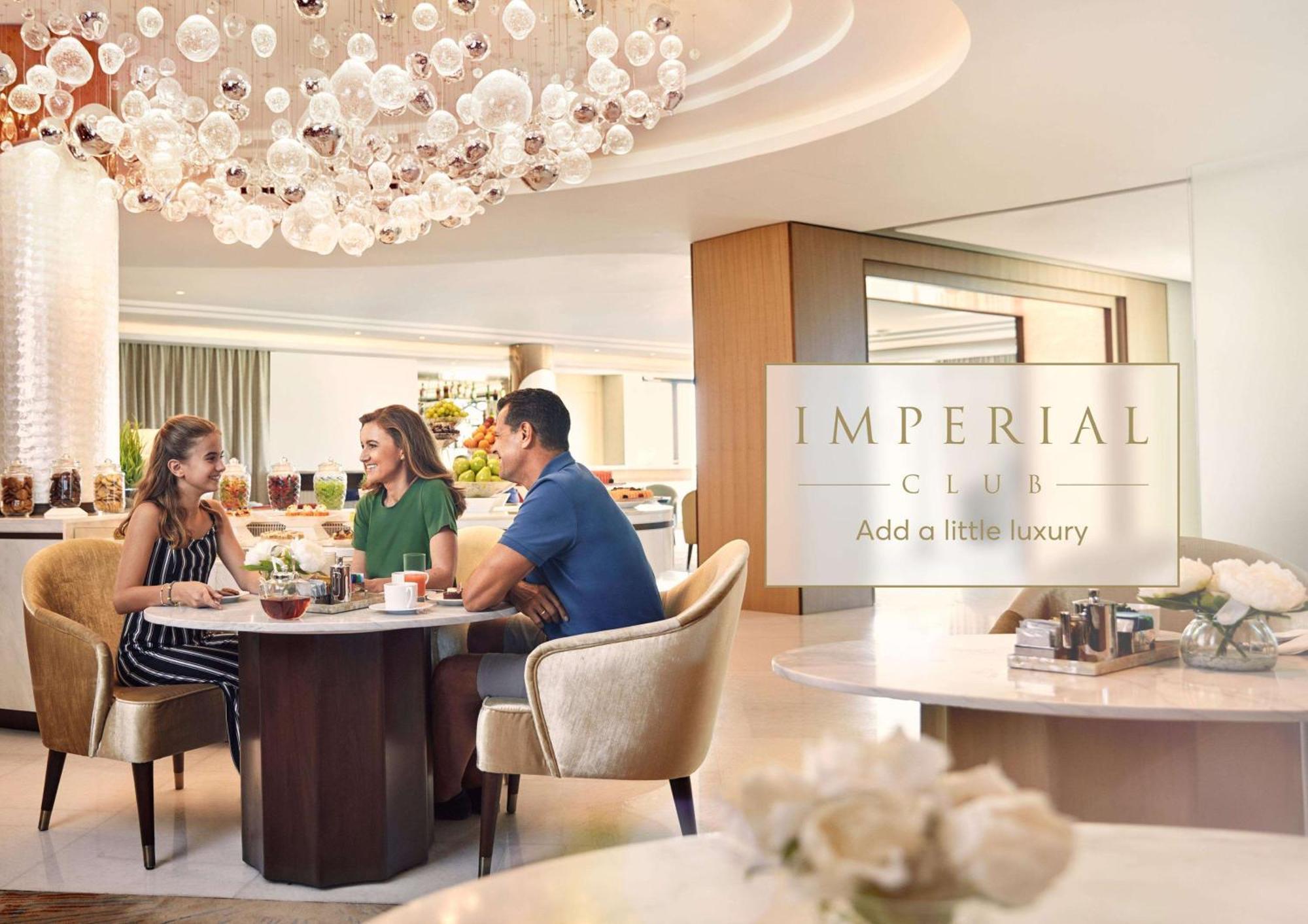 Hotel Atlantis, The Palm Dubai Esterno foto The photo shows a luxurious dining setting, likely in a restaurant or cafe. There are three people seated at a circular table, engaged in conversation. Two women and a man are enjoying drinks and possibly light snacks. The interior features elegant d