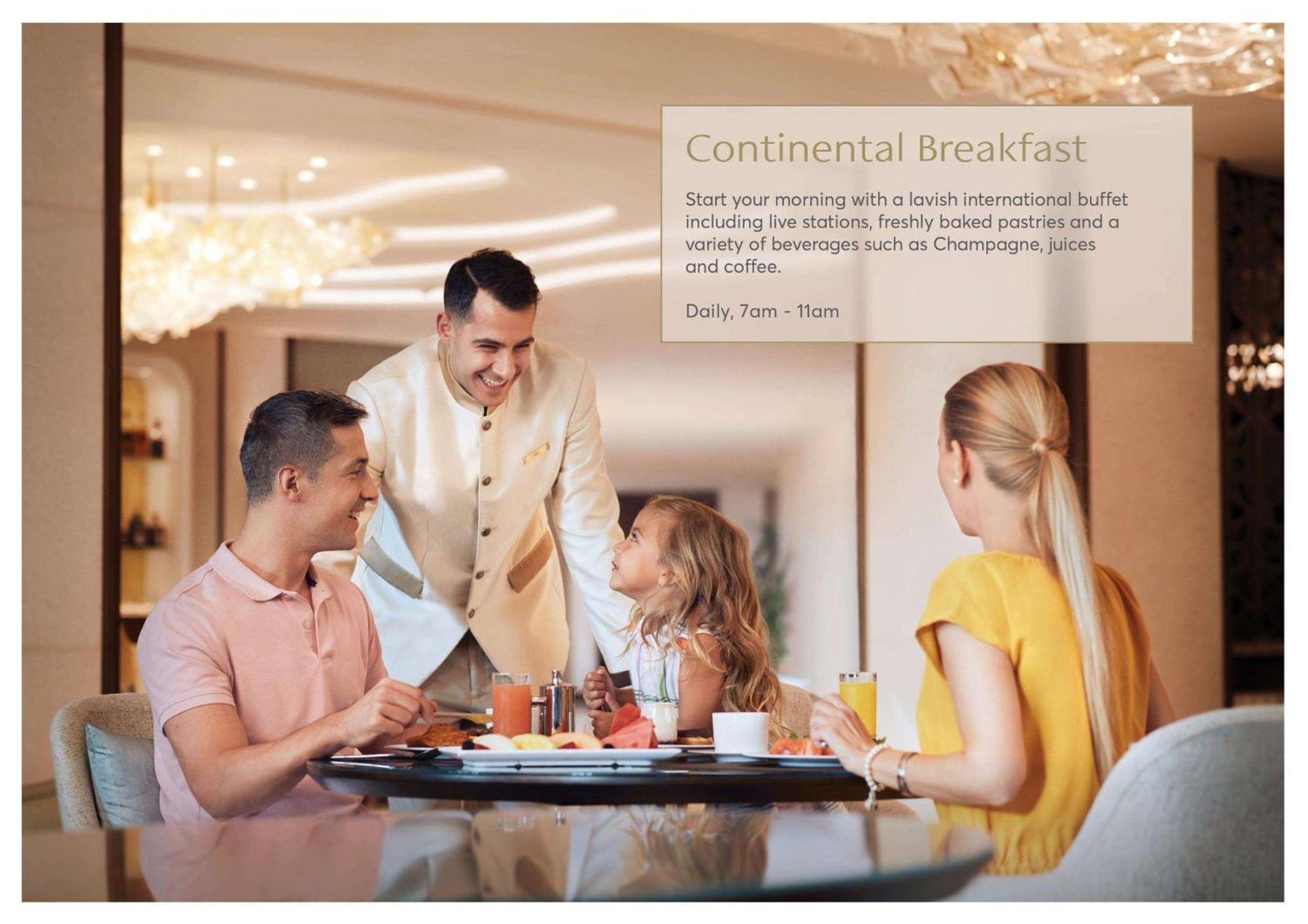 Hotel Atlantis, The Palm Dubai Esterno foto The photo depicts a warm and inviting breakfast scene in a dining area. A smiling male server, dressed in a formal outfit, is interacting with a family seated at a table. The family consists of two adults and a young girl. They appear to be enjoying 