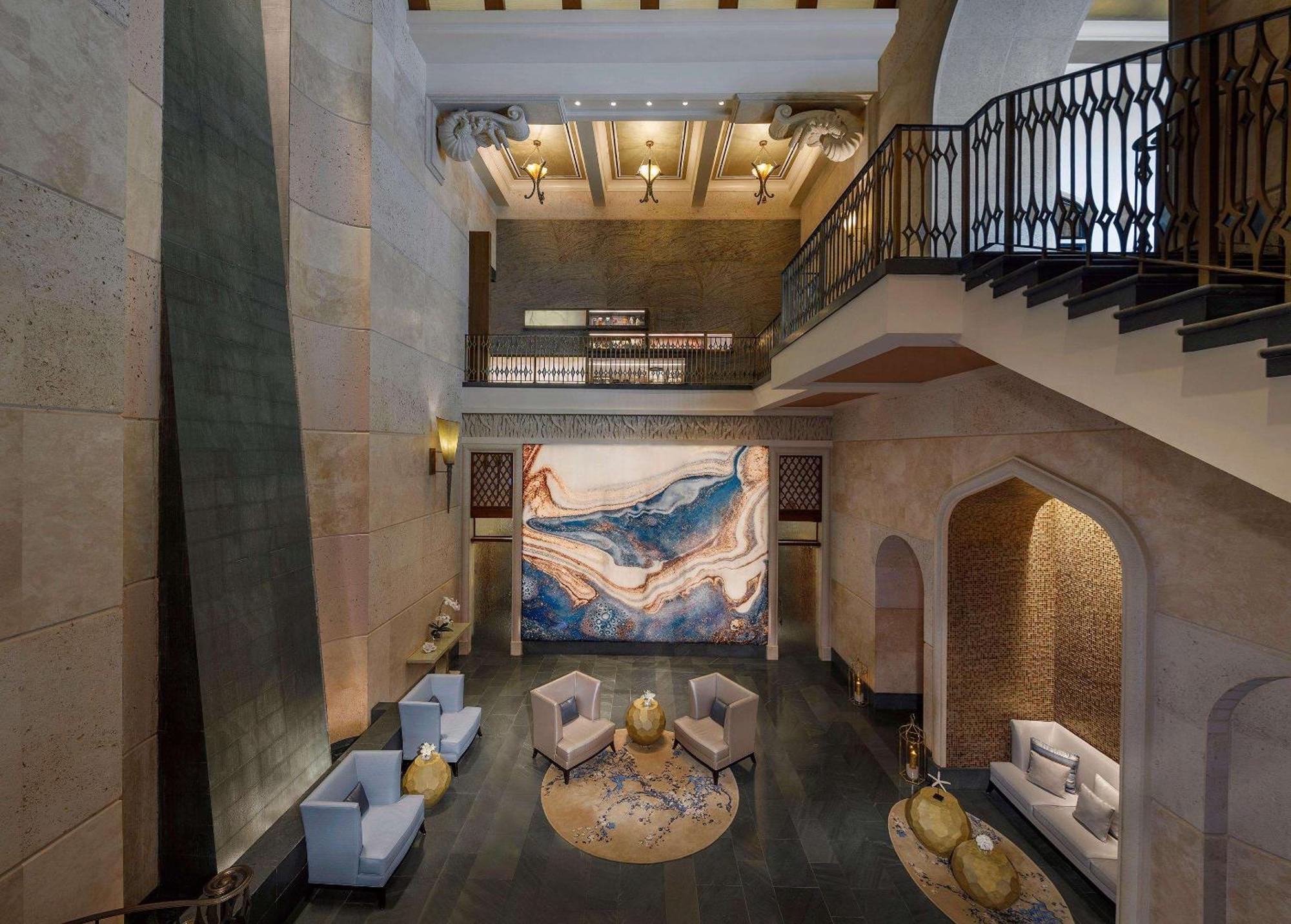 Hotel Atlantis, The Palm Dubai Esterno foto The photo depicts a spacious and elegantly designed interior, likely the lobby of a hotel or a building. The space features high ceilings with ornate architectural details and warm lighting. In the center, there is a large, striking piece of artwork 